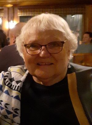 Snapshot of Jan, smiling with her head tilted to the side. She has a twinkle in her eyes.