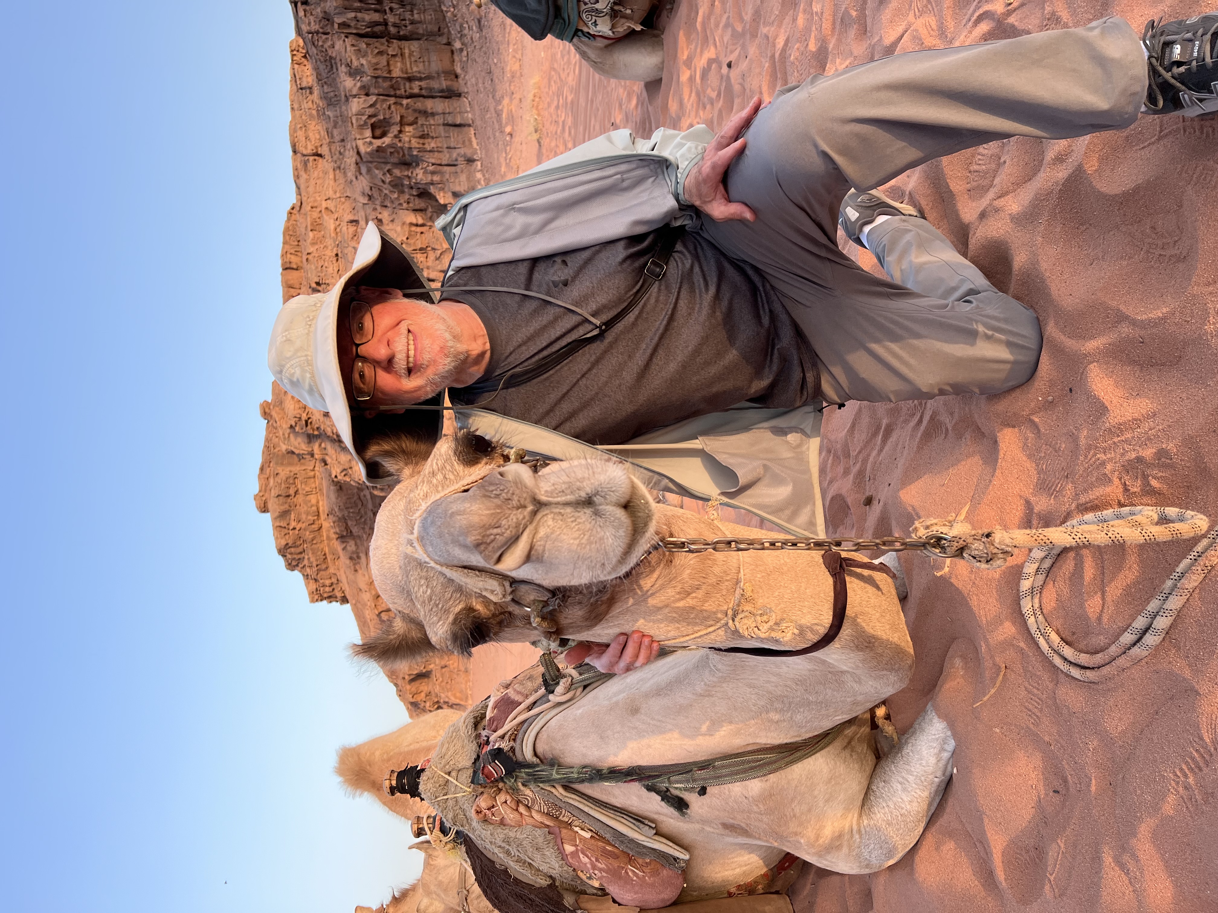 Bob posing with a camel in a desert setting. 