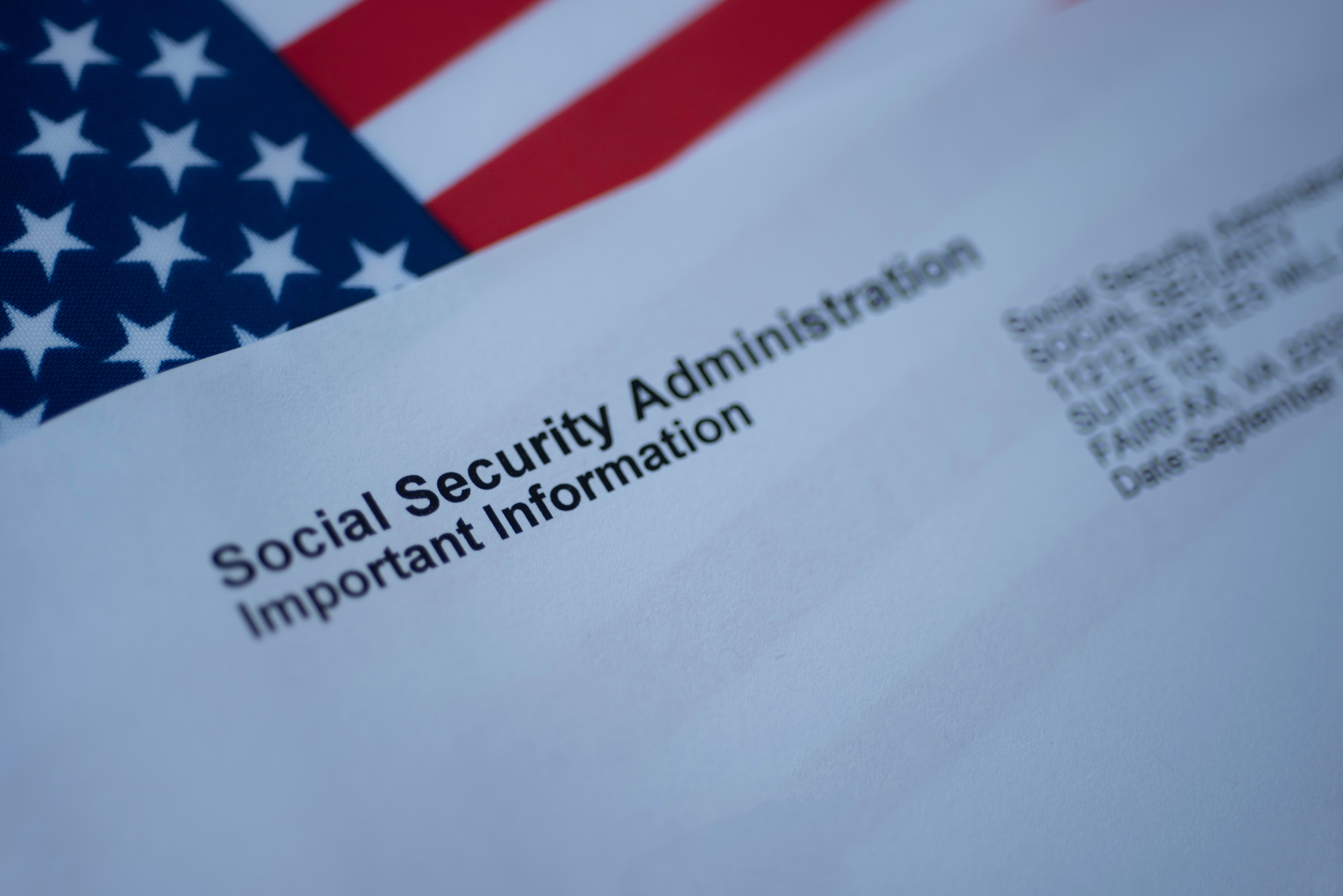 US flag in background. Envelope from Social Security Administration marked Important Information. Recipient's address is blurred out.