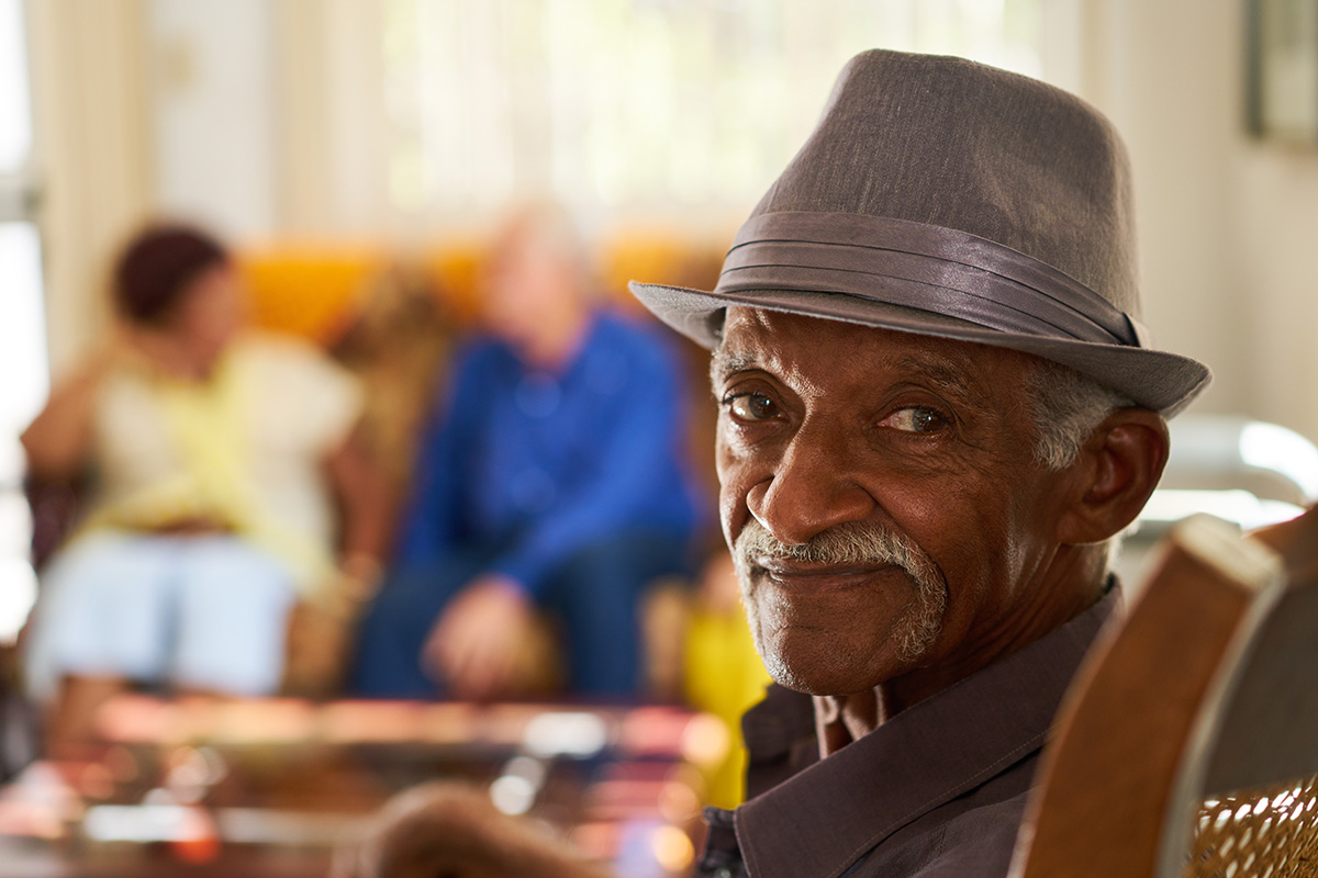 Senior African-American man wearing a fedora hat is looking at the camera.