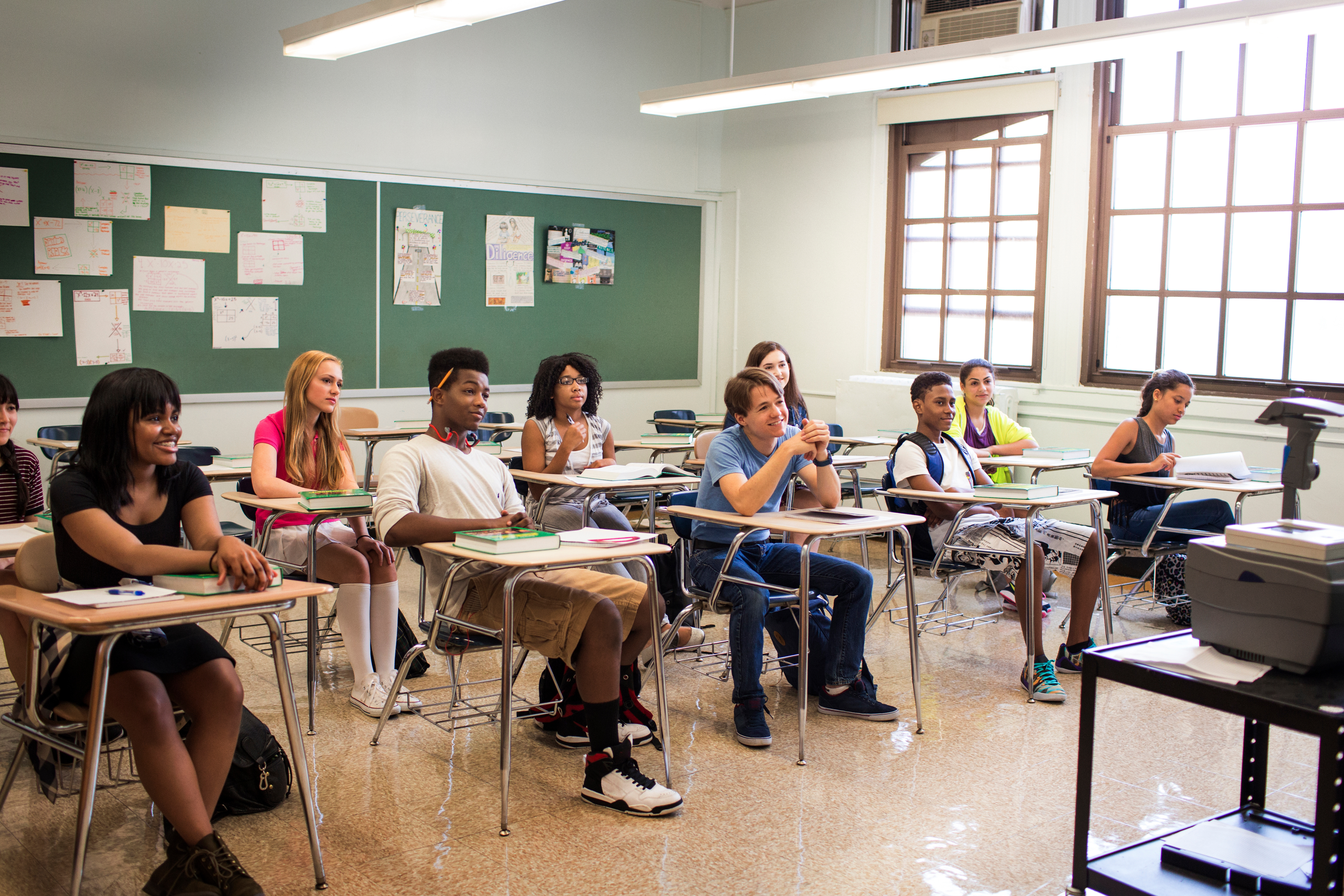 Students at their desks in a classroom, engaged in the teacher's lecture