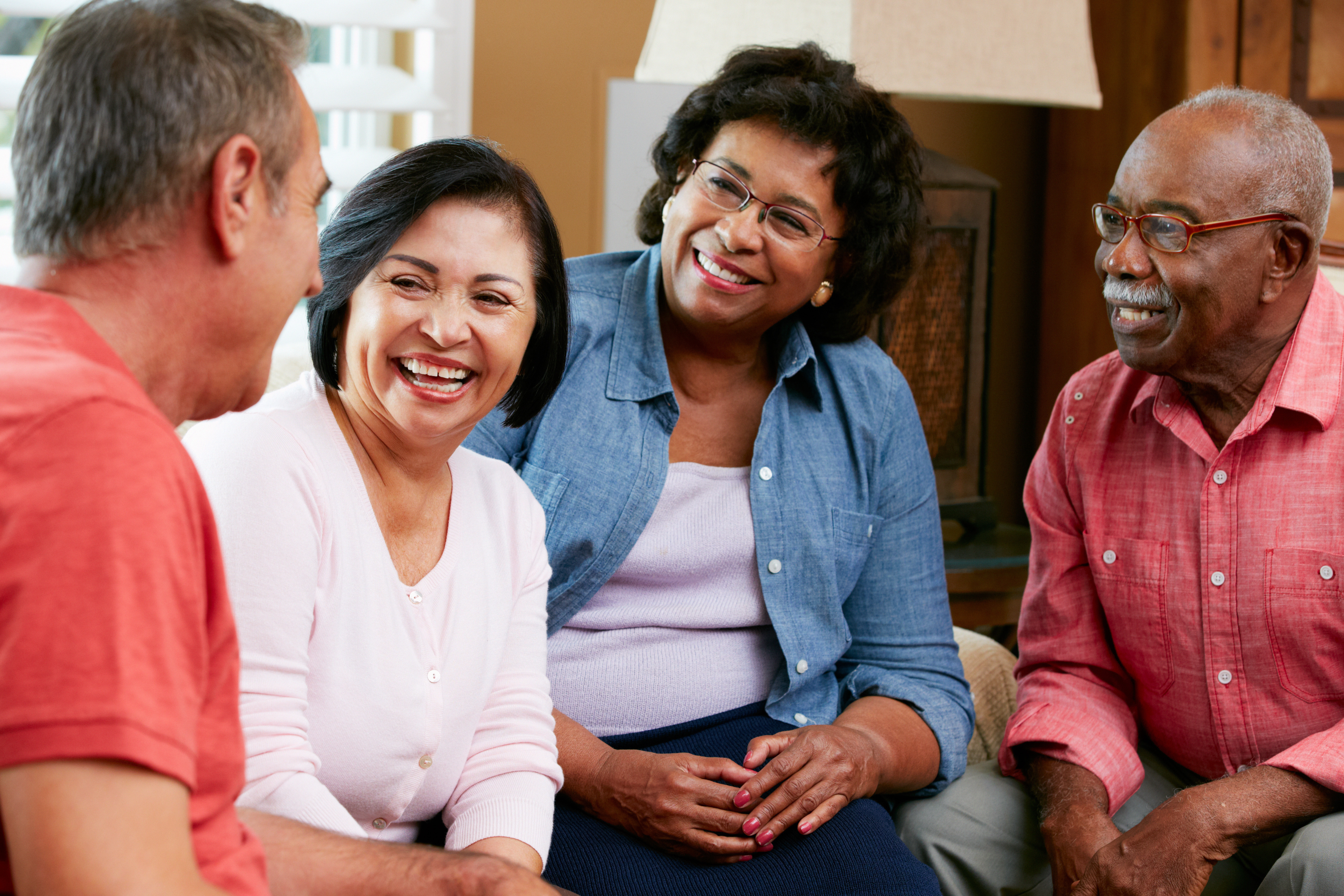 Group of older adults smiling and chatting in a living room.