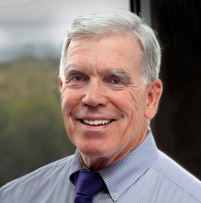Dr. Pat Zook, an older man, wears a button down shirt and tie and smiles at the camera.