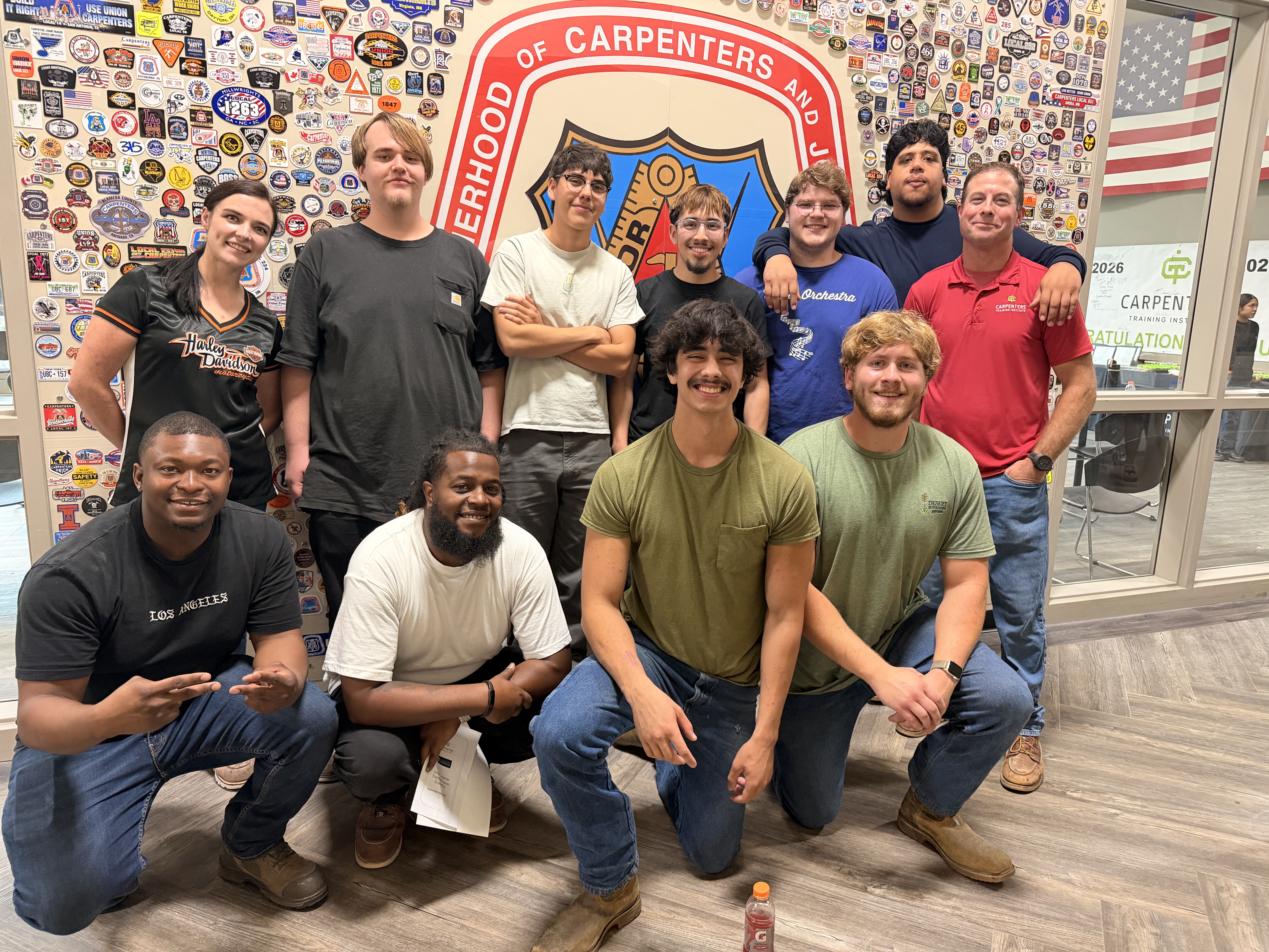 Union carpenter grads stand in front of carpenters union logo