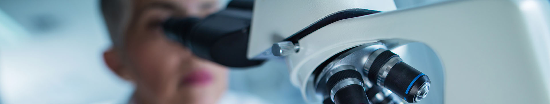 Banner image of a technician looking into a microscope