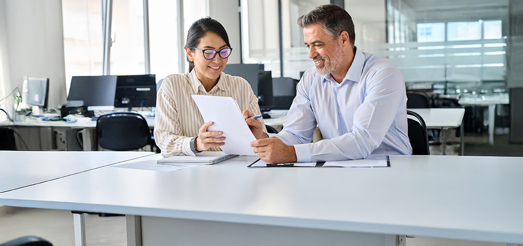Two employees at a desk reviewing a document