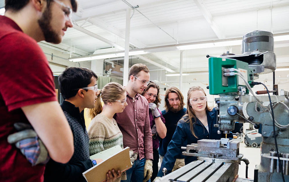 A group of students standing around a machine