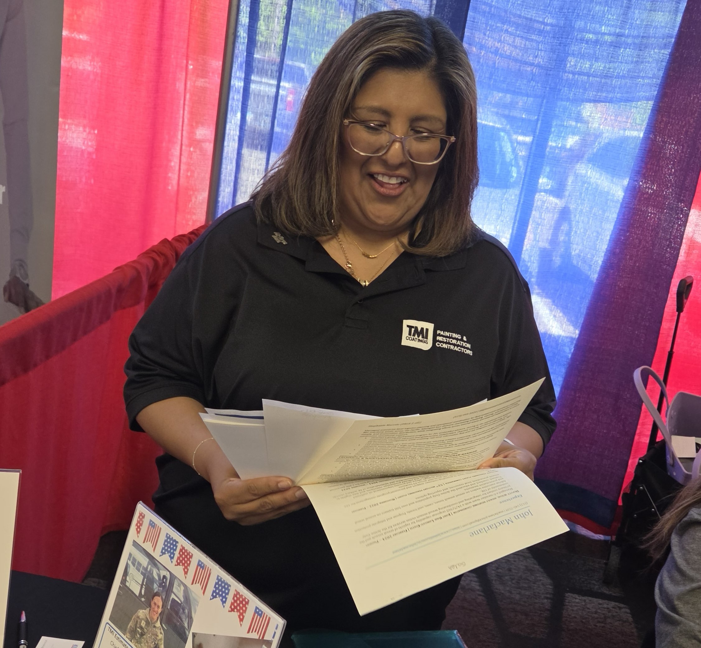 Lis smiles as she sits behind a booth, sorting through resumes she has received. Lis smiles as she sits behind a booth, sorting through resumes she has received.