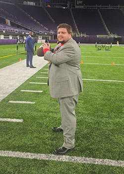 A man in a suit on a football field holding a football