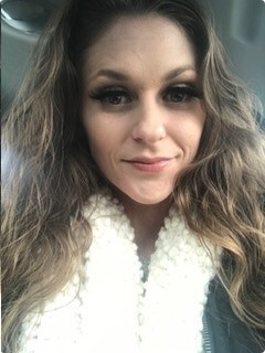 Kelli Turbes, a woman with long, wavy brown hair in a leather jacket with a white, fluffy lining.