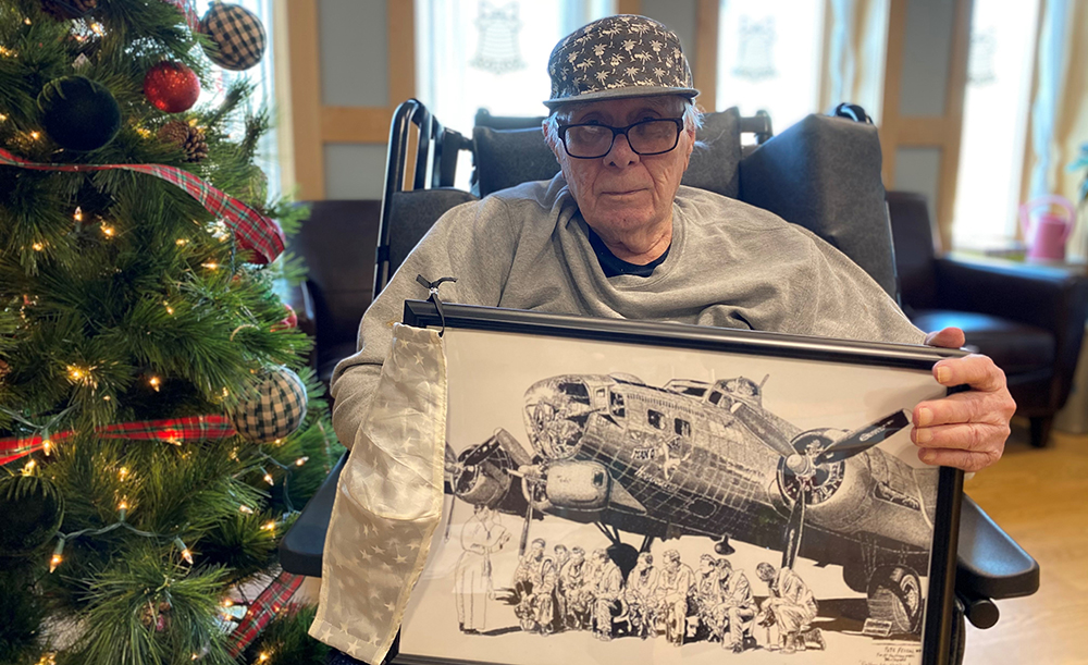 Resident by decorated tree with mask and photo of plane