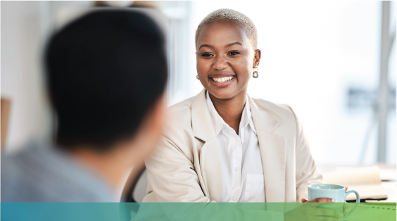 A woman smiling while facing another person whose back is to the camera and their image is blurred.