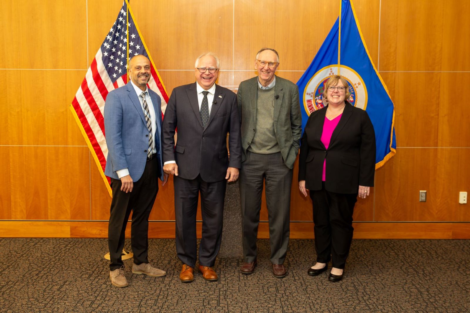 People pose for a photo in front of flags