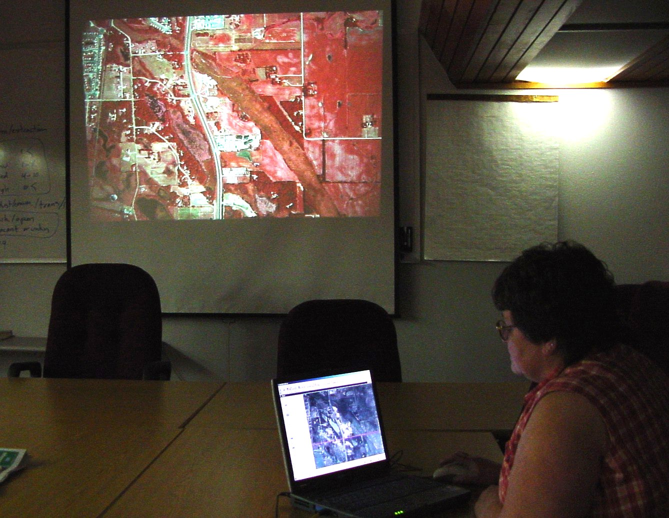 Person on a laptop with a large screen showing satellite imagery