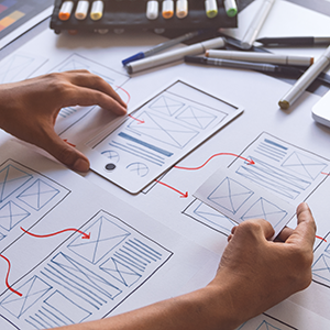 Hands laying out a paper web application prototype