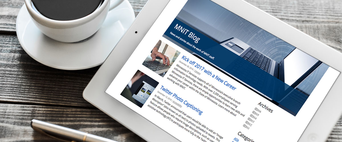 A table with a cup of coffee and digital tablet the Minnesota IT Services' Blog. 