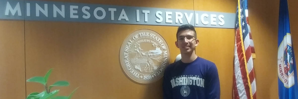 Photo of Andre Magallanes standing in front of the Minnesota IT Services sign