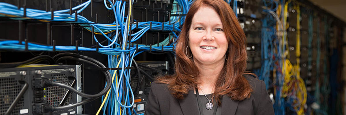 Brenda Gabriel standing in front of the a row of computer servers.