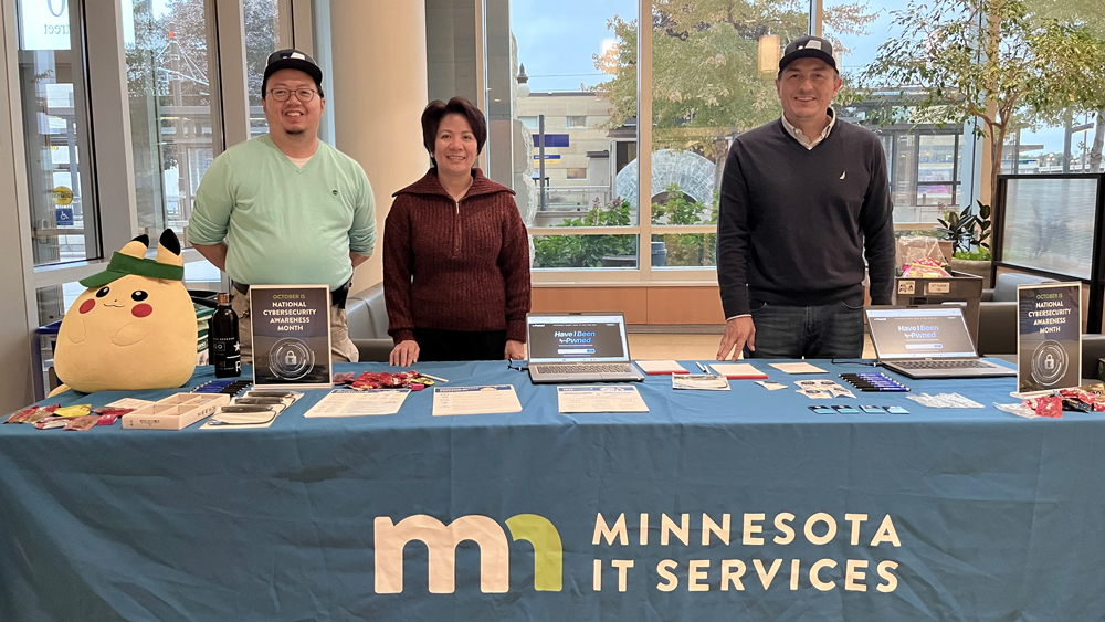 State employees working at a table with Cybersecurity Awareness Month informational materials.