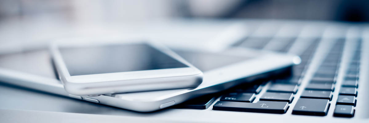 A cellphone and electronic tablet laying on top of a laptop.