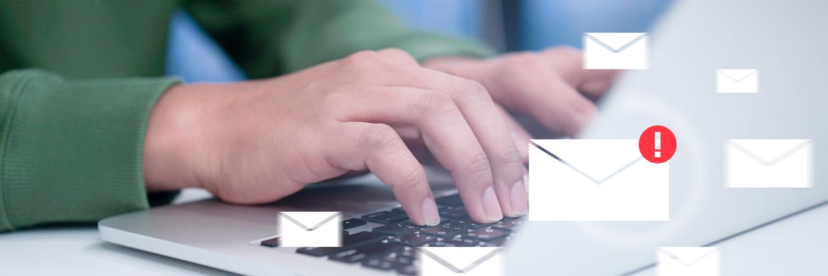 Email icons floating in front of a person typing on a laptop.