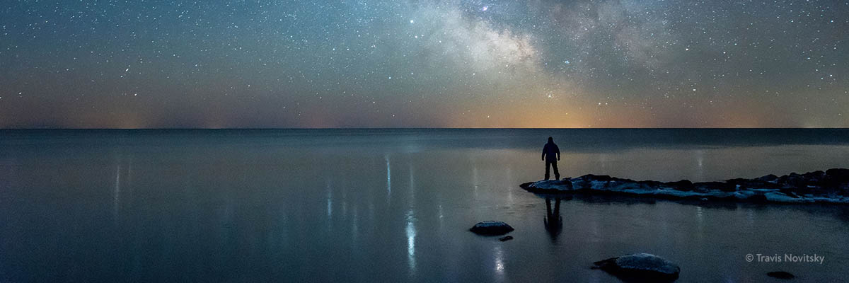 Person looking at the night sky over a lake.