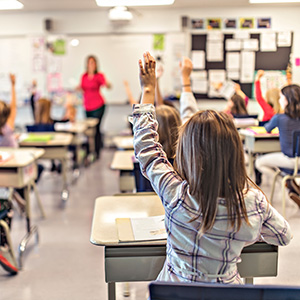A child raising their hand in a classroom