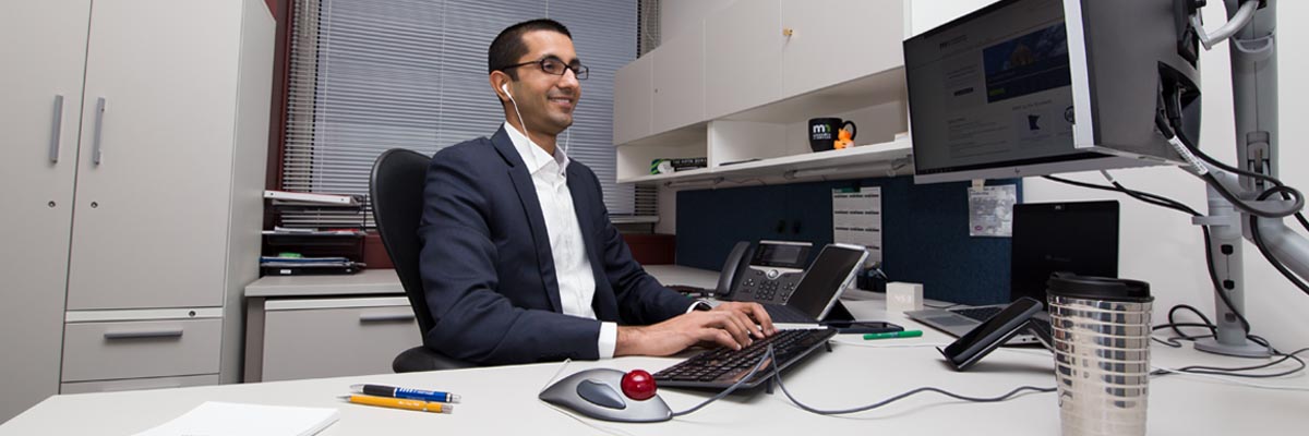Rohit Tandon sitting at his desk working on a computer while listening to an ipod.
