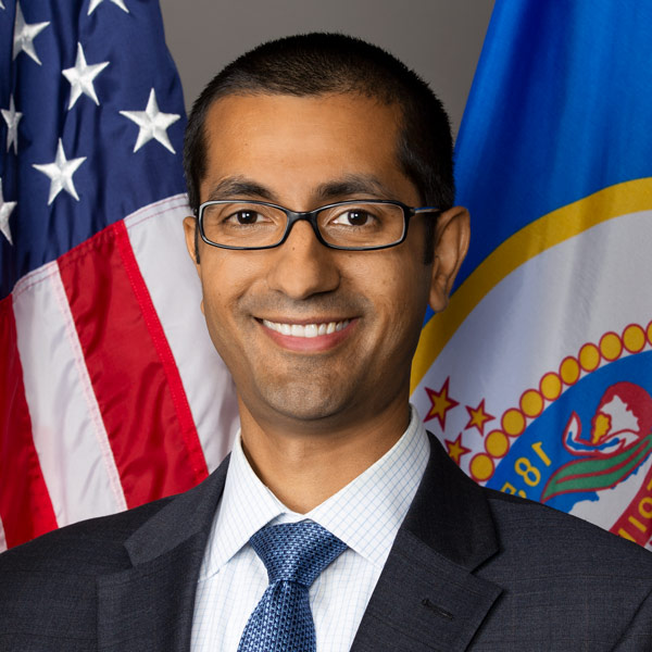 Headshot of Rohit Tandon in front of a flag.
