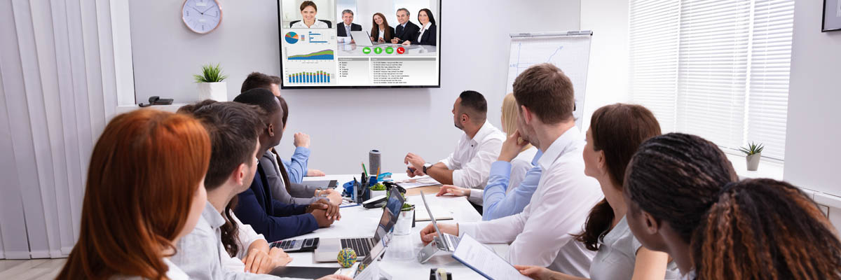 Group of people meeting with another group via web conference.