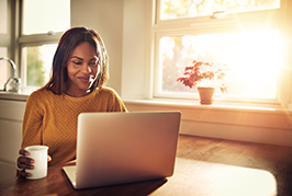 Woman sitting at a laptop drinking coffee in the morning