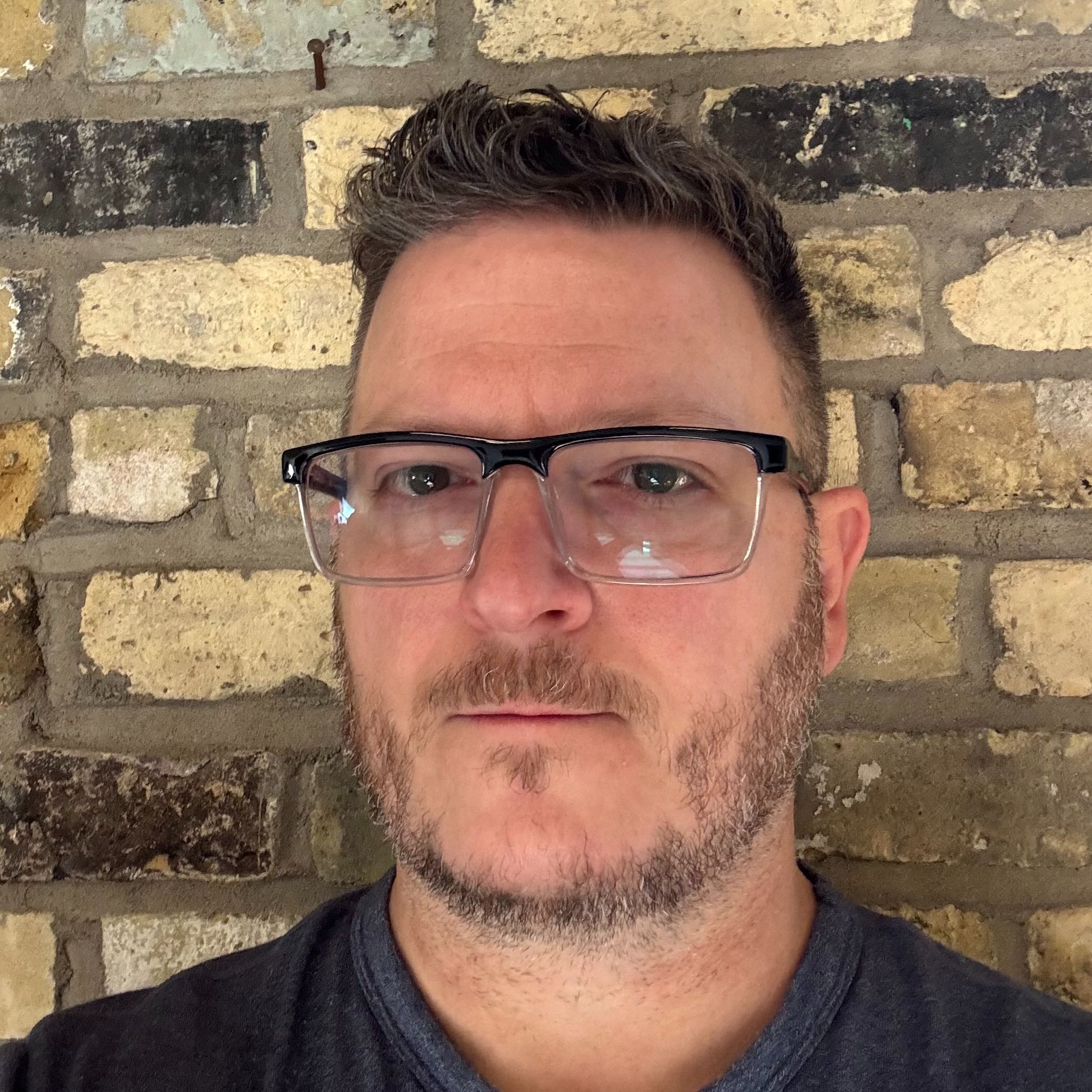 Adam is a man with white skin, short dark hair, glasses, and a short beard.