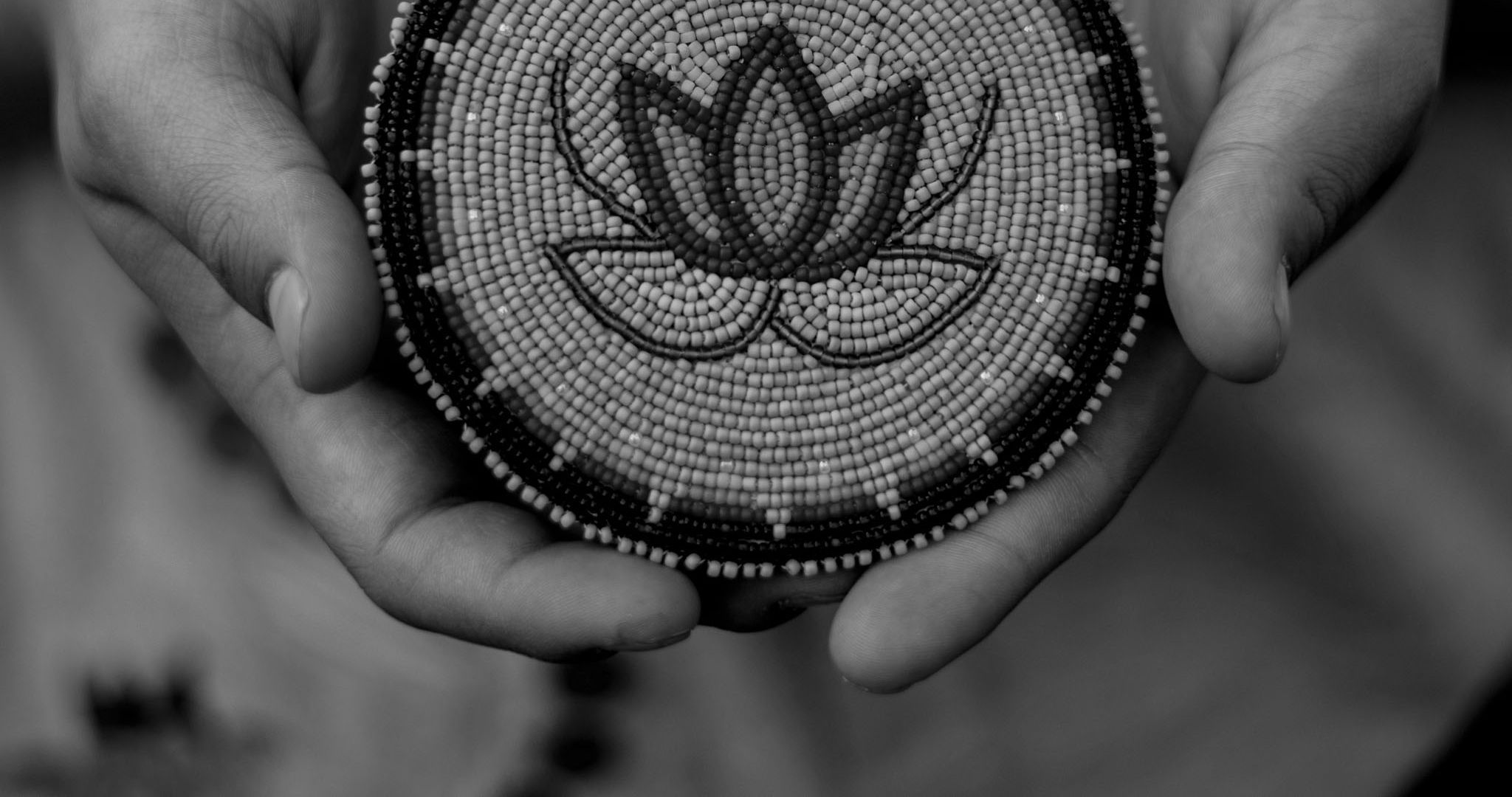 hands holding a beaded medallion