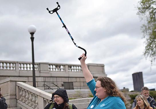 Aya from St Cloud, foreground, raised her cane during a TakeAction Minnesota teach-in held in response to proposed Senate health care cuts.