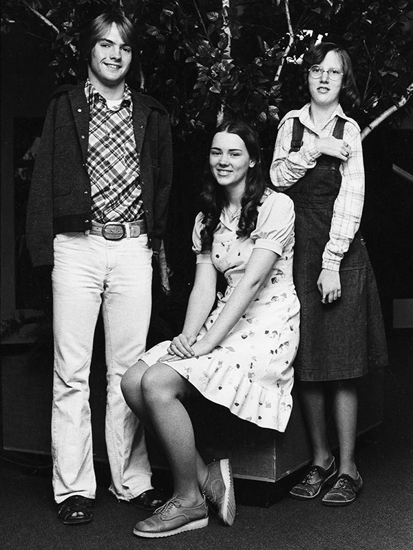 Photo of three children of high-school age sitting for a formal photograph, one boy and two girls