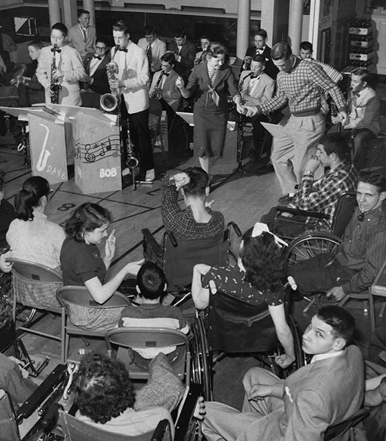 A band plays as teenagers with disabilities clap and participate in the show.