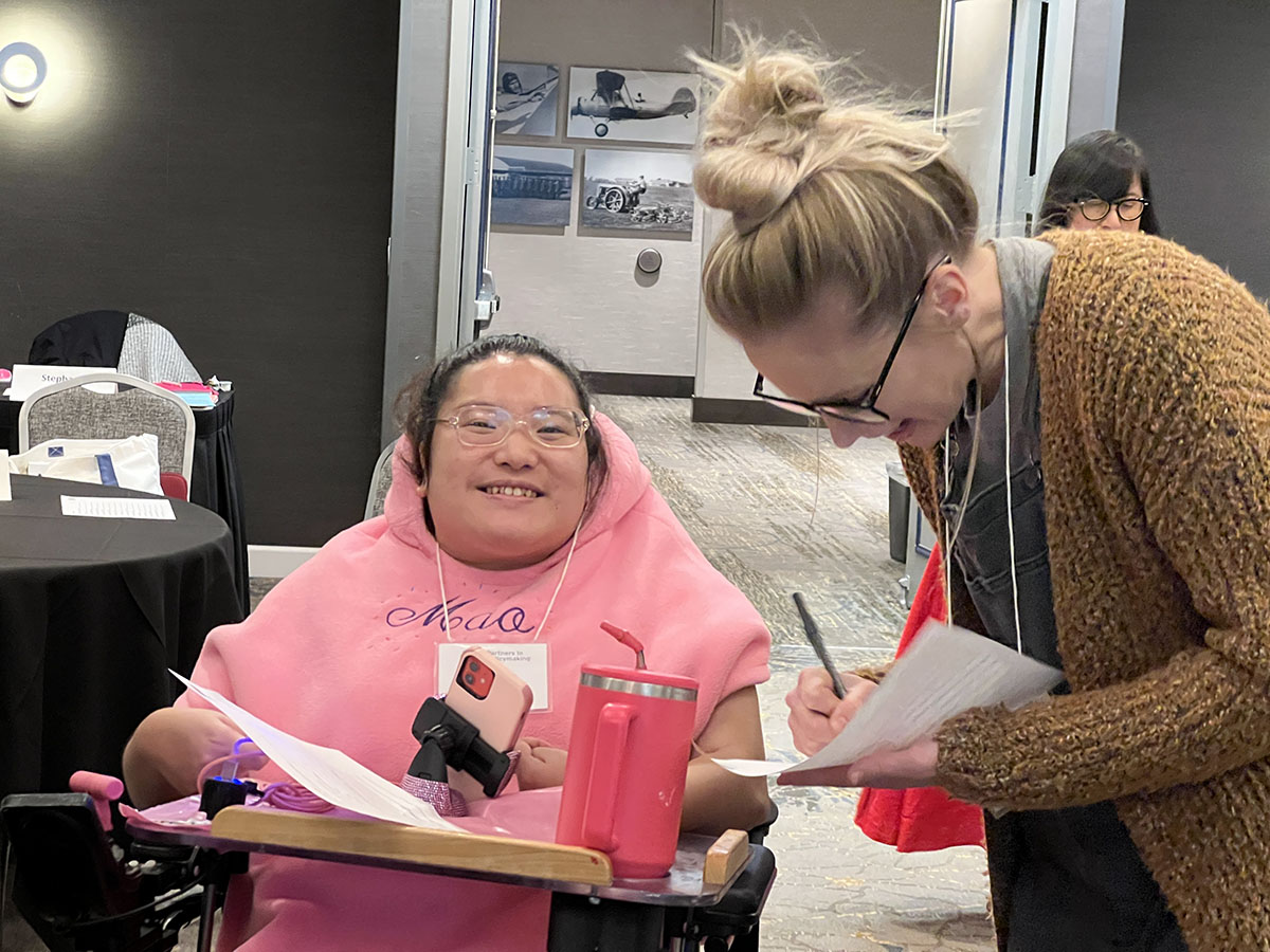 Class 42 October Session - smiling woman in wheelchair and friend